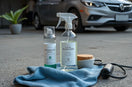 Eco-friendly car cleaning items and reusable cloth arranged beside a modern car exterior in daylight