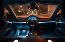 Car cabin at night with softly glowing LED strips along the dashboard and footwell