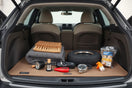 Neatly arranged automotive cleaning and safety gadgets on a car trunk mat