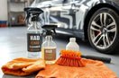 Durable car cleaning tools and bottles arranged beside a partially washed car in a garage