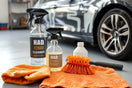 Durable car cleaning tools and bottles arranged beside a partially washed car in a garage