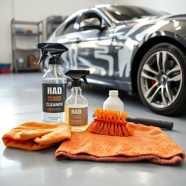 Durable car cleaning tools and bottles arranged beside a partially washed car in a garage