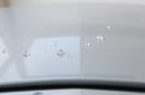 Water beads forming on a coated car hood surface under soft daylight