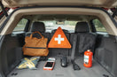 Safety accessories arranged in a car trunk and interior, including a first-aid kit and warning triangle