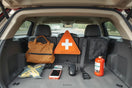 Safety accessories arranged in a car trunk and interior, including a first-aid kit and warning triangle