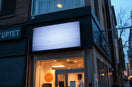 Bright dynamic LED signage on a storefront facade at dusk, glowing with subtle animated light patterns