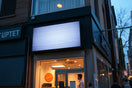 Bright dynamic LED signage on a storefront facade at dusk, glowing with subtle animated light patterns