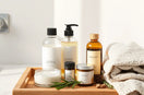 Natural hair care products on a wooden tray with botanical ingredients and towel beside a countertop