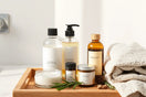 Natural hair care products on a wooden tray with botanical ingredients and towel beside a countertop