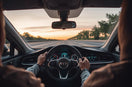 Driver controls a modern car while dashboard safety monitoring is visible in a clean interior scene