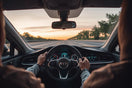 Driver controls a modern car while dashboard safety monitoring is visible in a clean interior scene