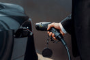 a man in a suit is pumping gas into a car