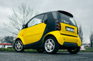 a yellow smart car parked on the side of the road