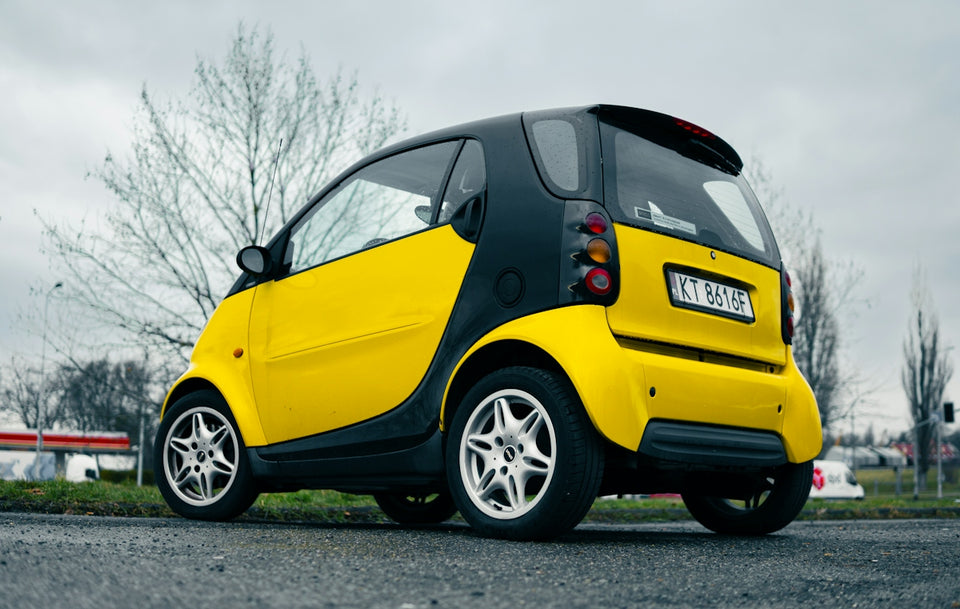 a yellow smart car parked on the side of the road