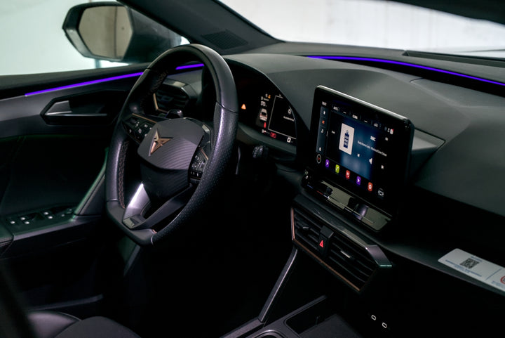 Modern car interior with illuminated dashboard and touchscreen.