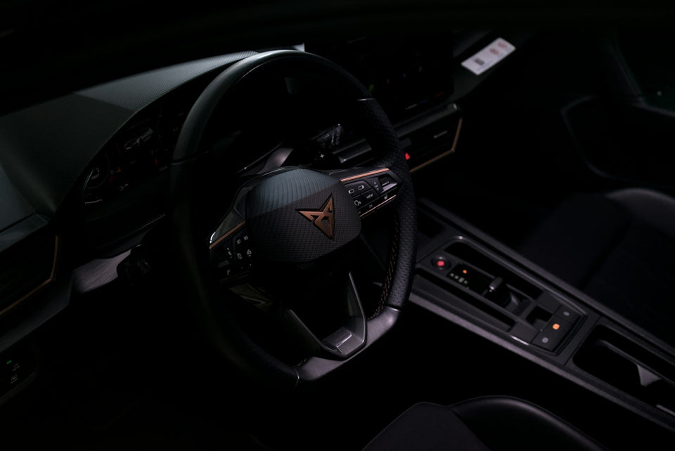 Dark car interior with a prominent steering wheel and controls