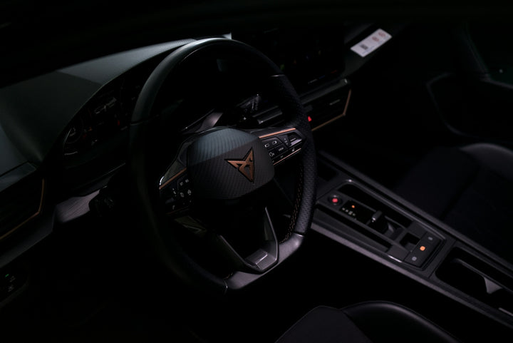 Dark car interior with a prominent steering wheel and controls