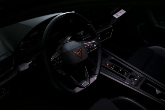 Dark car interior with a prominent steering wheel and controls